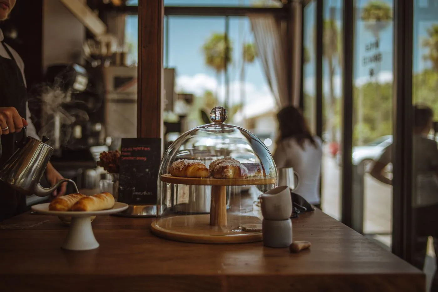 Illustrative: a warm local coffee shop counter with pastries and morning light